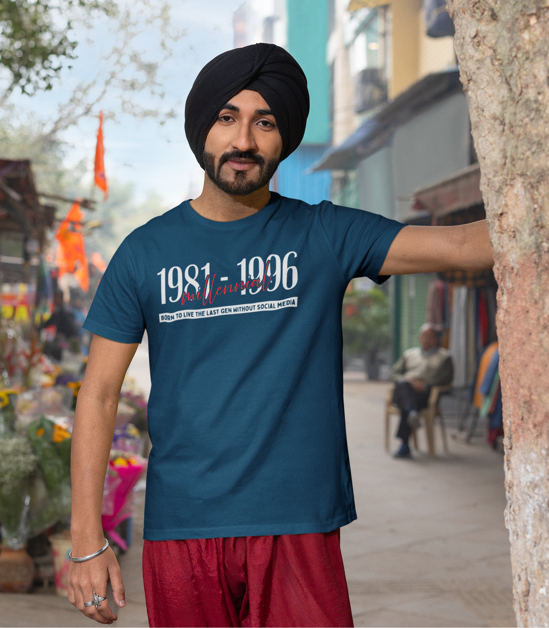 Man wearing a blue t-shirt with text, standing in an outdoor market setting.