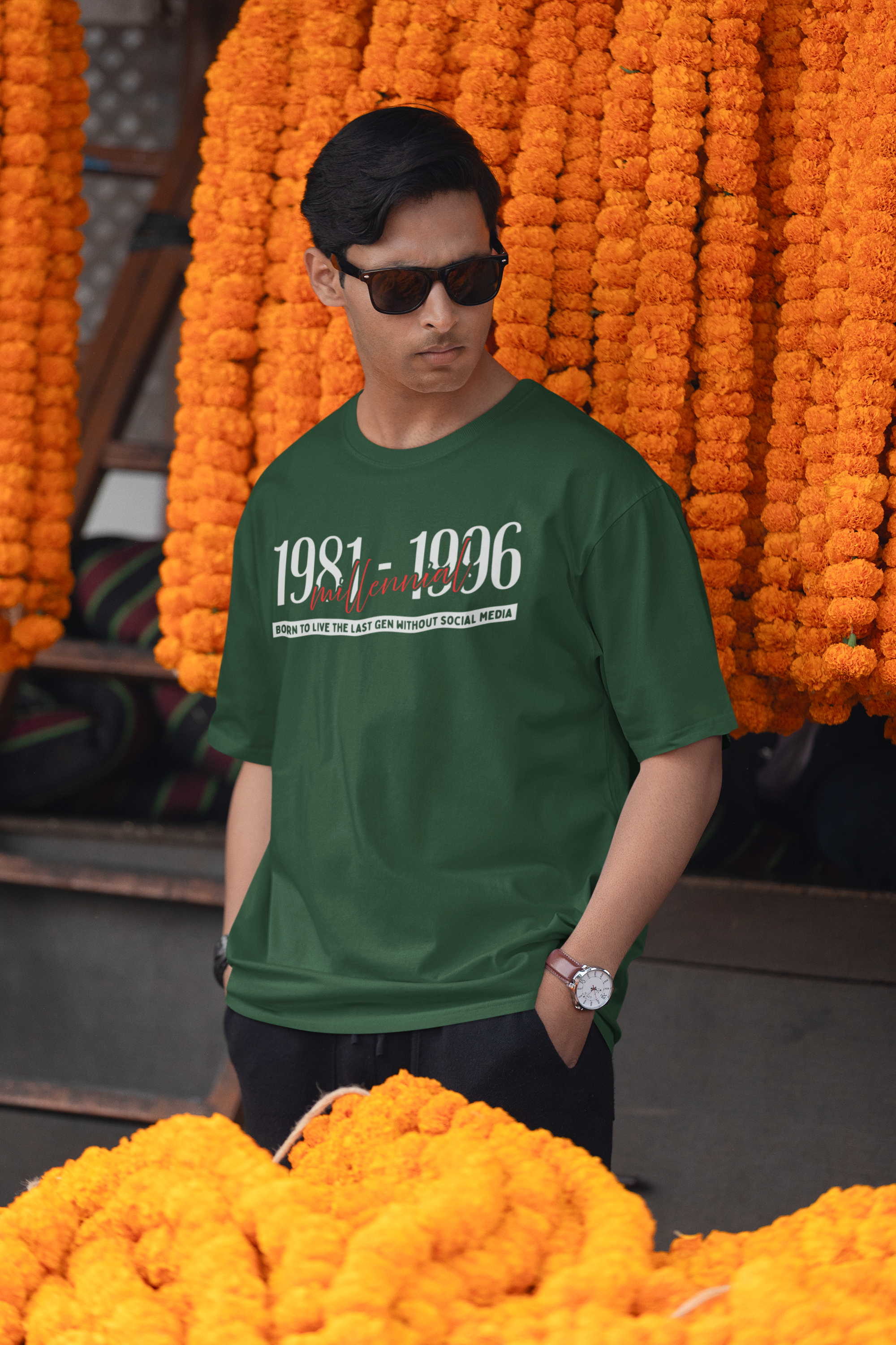 Man wearing a green t-shirt with text standing in front of orange floral decorations.