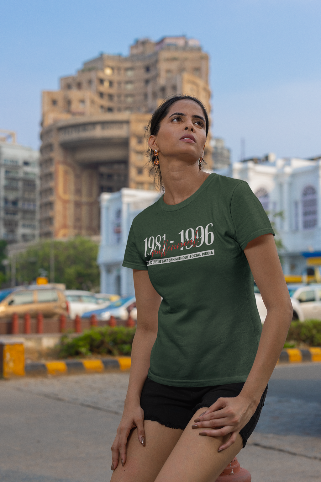 Woman wearing a green t-shirt with text standing on a street with buildings in the background
