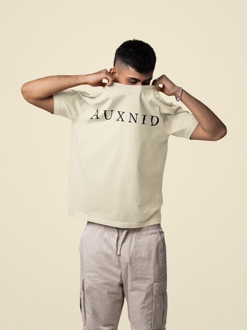 Person wearing a beige t-shirt with 'AUXNID' printed on it against a beige background