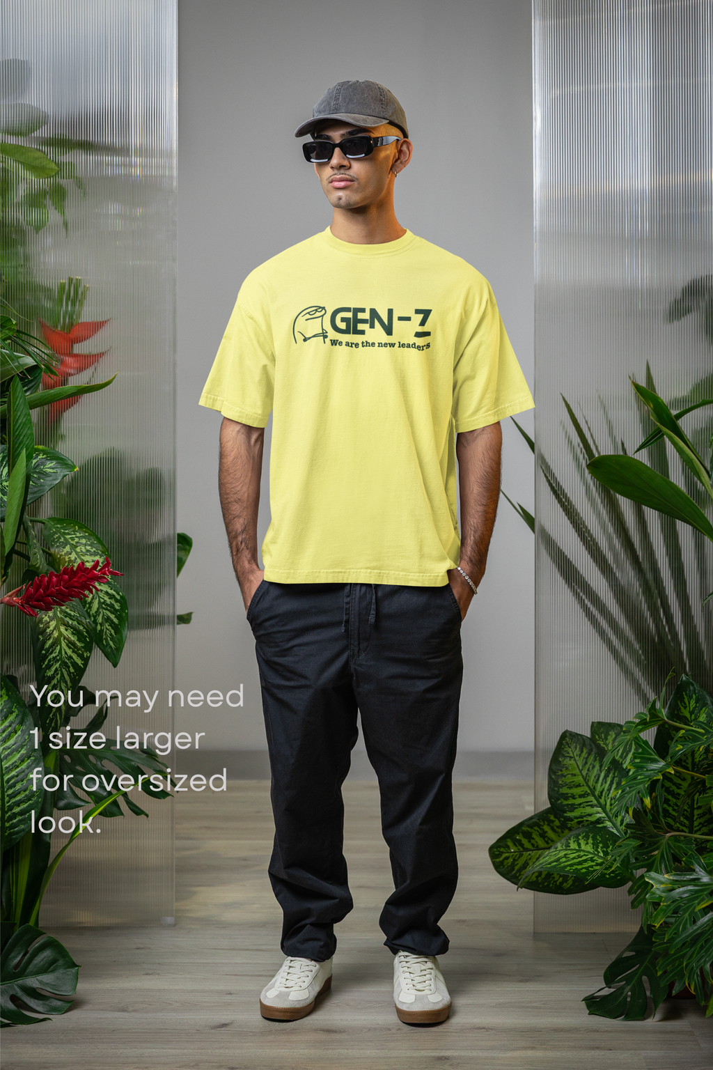 Person wearing a yellow t-shirt with 'GEN-Z' logo and dark pants, standing indoors with plants.