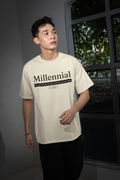 Man wearing a beige t-shirt with 'Millennial' text in an indoor setting.