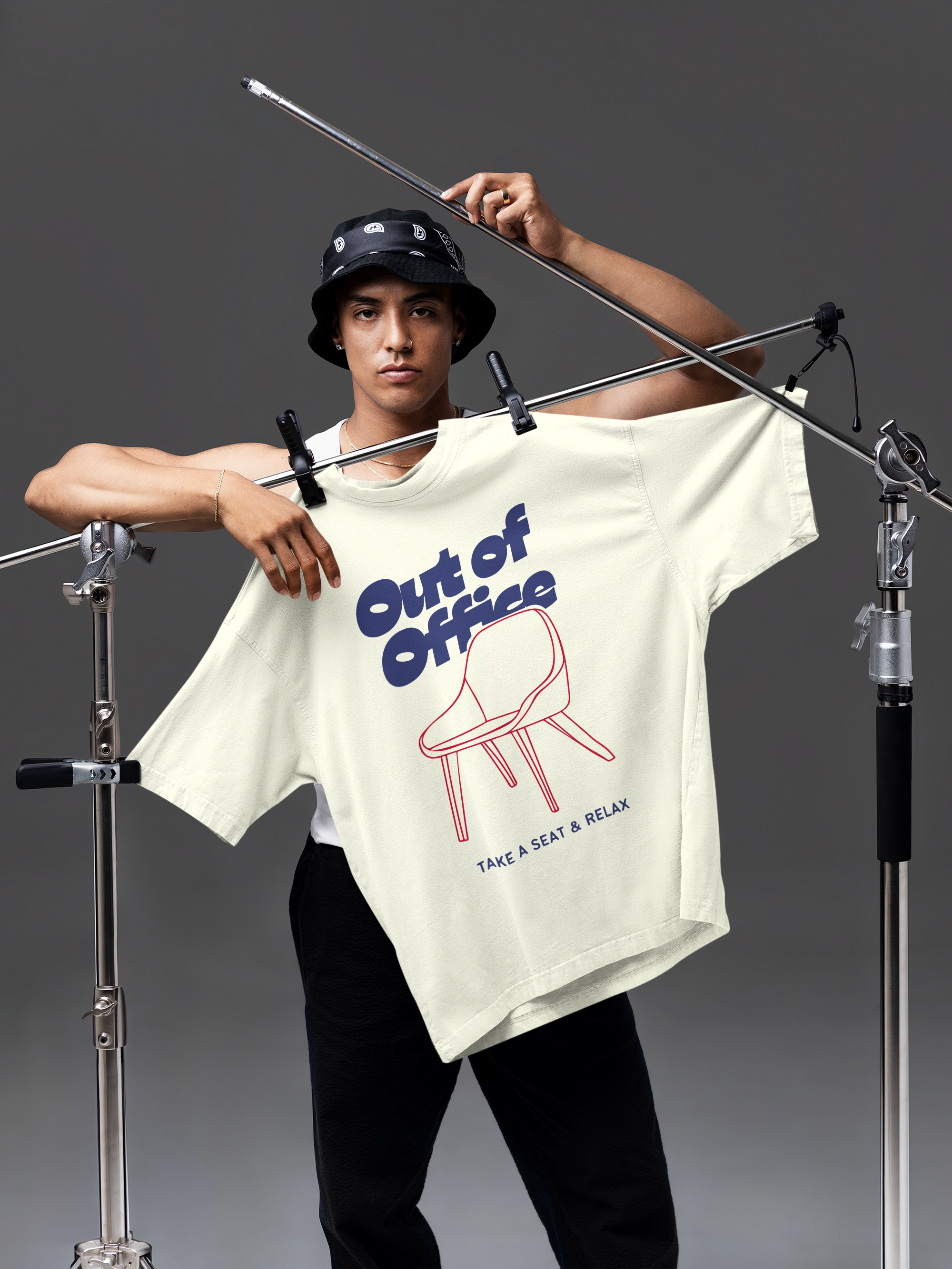 Person holding a t-shirt with 'Out of Office' design on a gray background