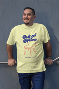 Man wearing a light green t-shirt with 'Out of Office' design against a blue wall.