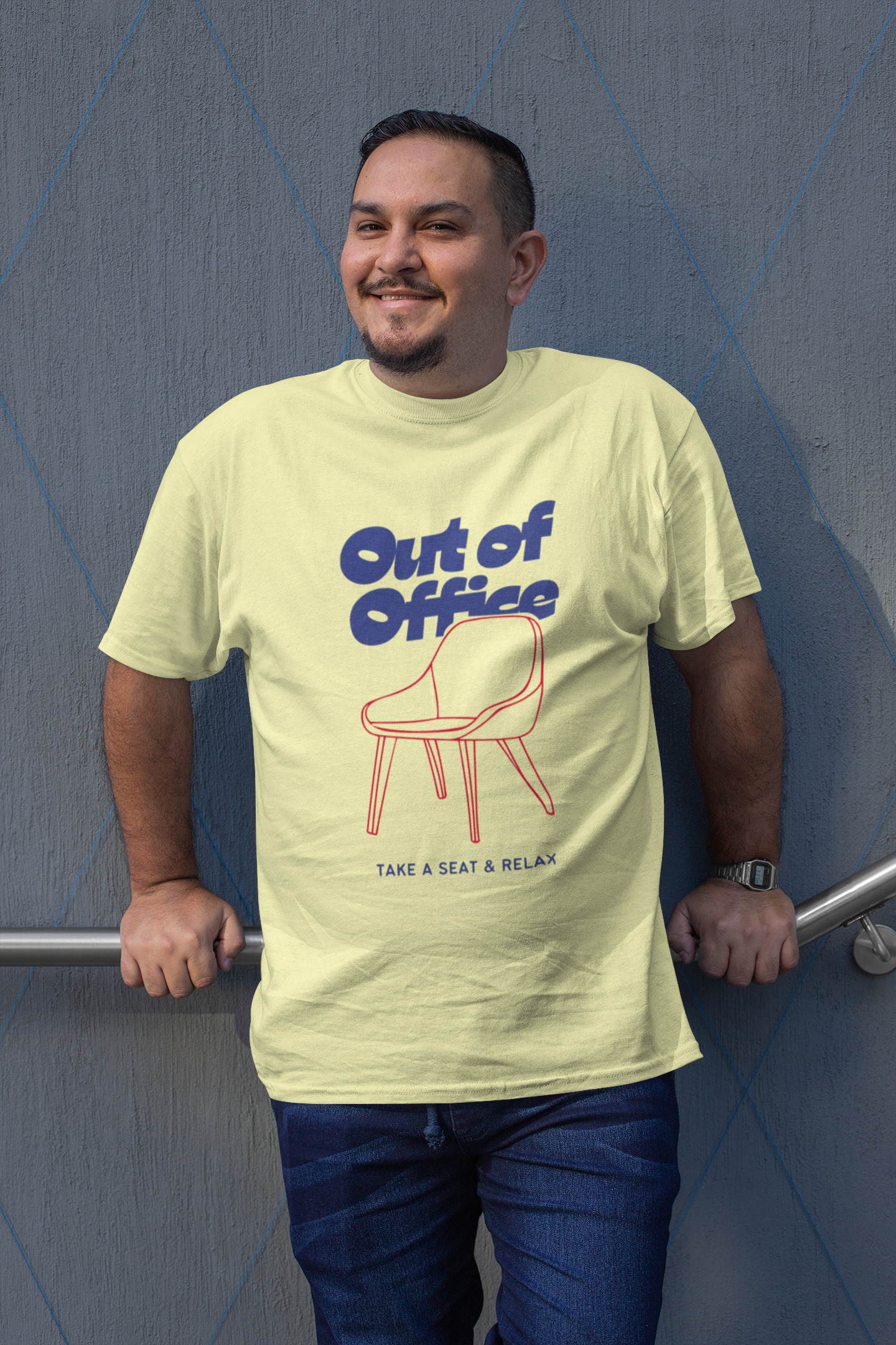 Man wearing a light green t-shirt with 'Out of Office' design against a blue wall.