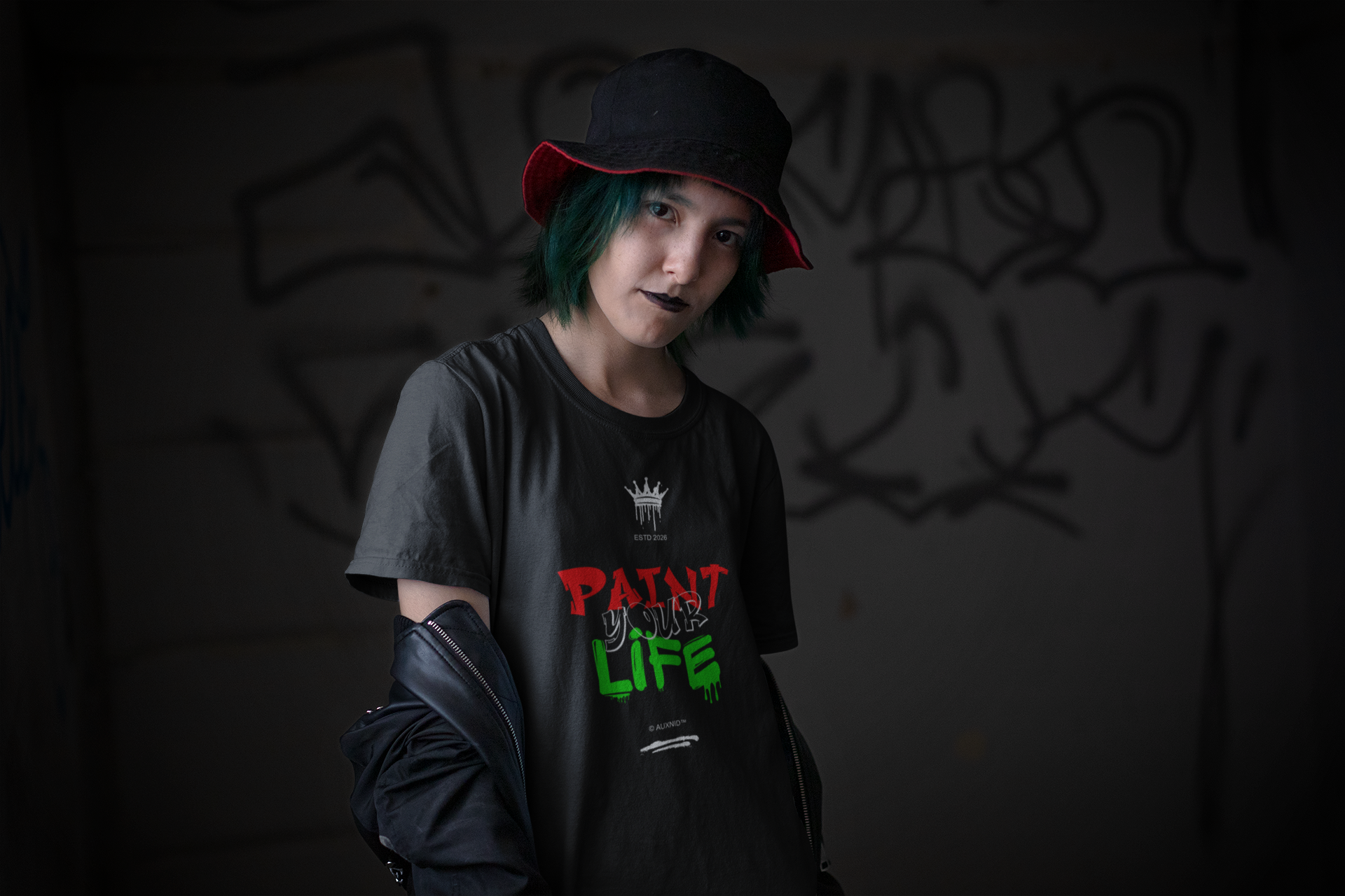 Person wearing a black t-shirt with colorful text and a black hat in a dark setting