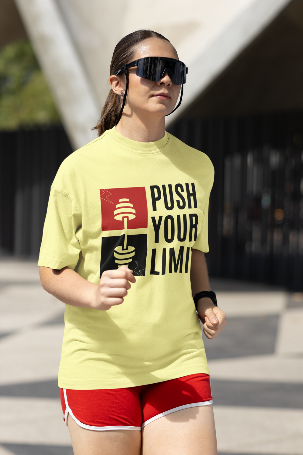 Person wearing a yellow t-shirt with 'Push Your Limit' text and red shorts outdoors.