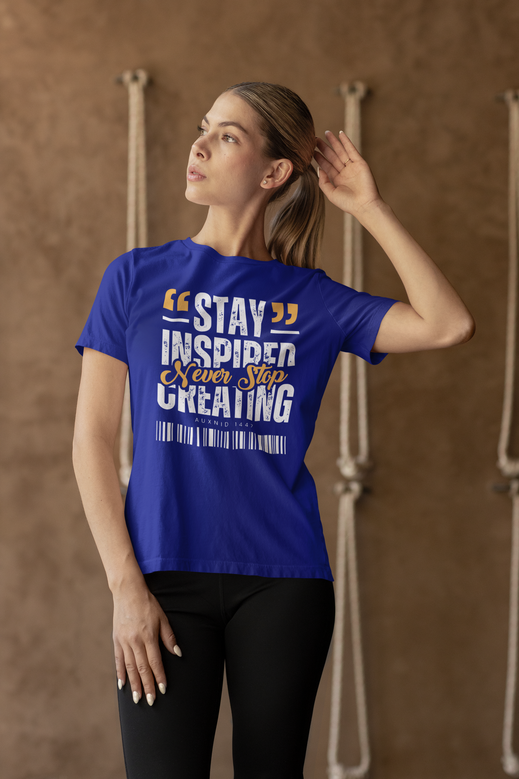 Woman wearing a blue t-shirt with motivational text against a brown background