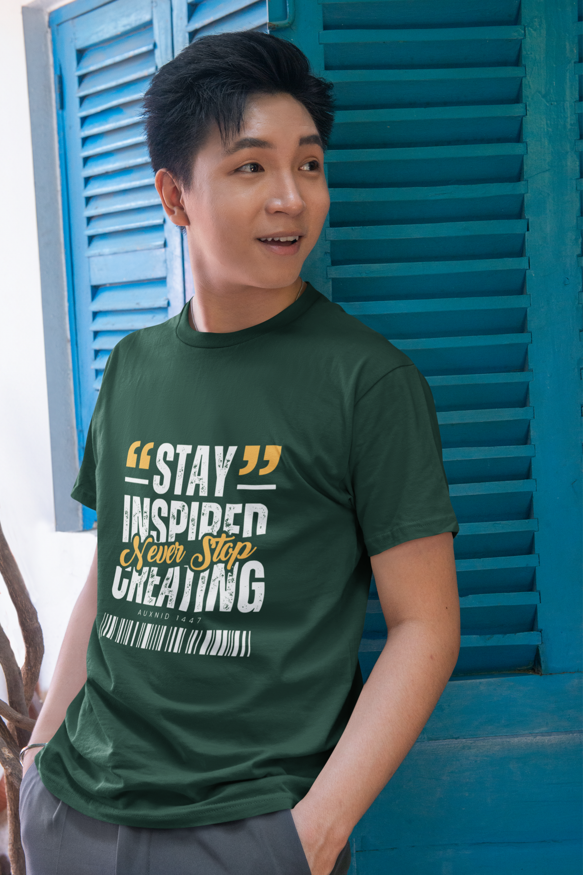 Person wearing a green t-shirt with motivational quote in front of blue shutters